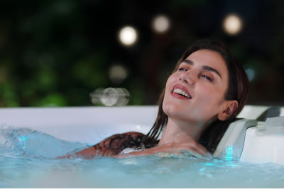 Eine junge Frau geniesst das warme Wasser und entspannt sich bei einer intensiven Massage in einem Whirlpool im Garten.