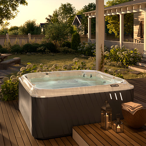 Jacuzzi J-200 Comfort Modell Whirlpool auf Holzterrasse im Garten bei Sonnenuntergang.