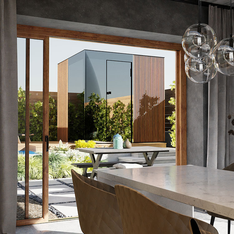 Moderne Gartensauna mit Glasfront und Holzlamellen, Blick aus einem stilvollen Essbereich.