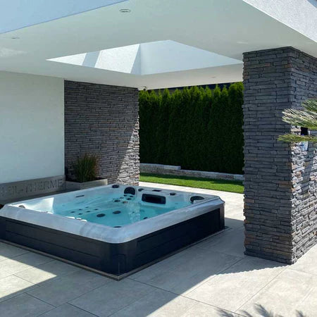 Outdoor Whirlpool vor dem Haus. Elegant im Boden versenkt und von Steinplatten umgeben.