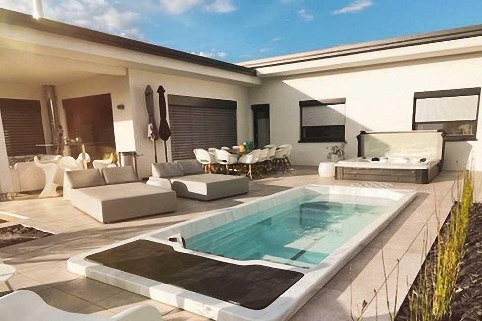 Fully-Inground Swim Spa in einem modernen Garten mit Terrasse und Loungemöbeln.