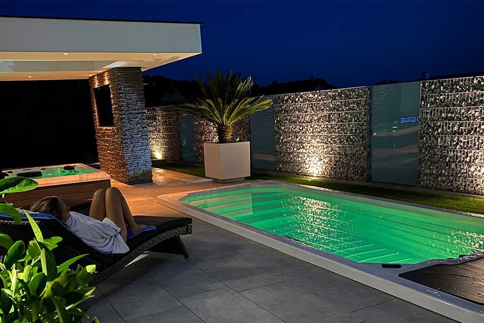 Fully Inground bodenversenkter Swim Spa auf moderner Terrasse bei Nacht mit stimmungsvoller Beleuchtung und entspannter Atmosphäre.