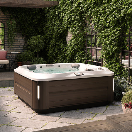 Jacuzzi J-300 Premium Whirlpool mit PowerPro Massagedüsen auf einer begrünten Terrasse.