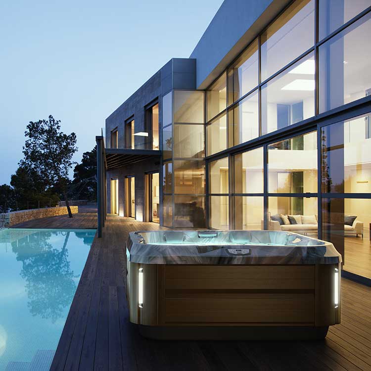Jacuzzi Spa auf moderner Terrasse mit Infinity-Pool und beeindruckender Architektur im Hintergrund.