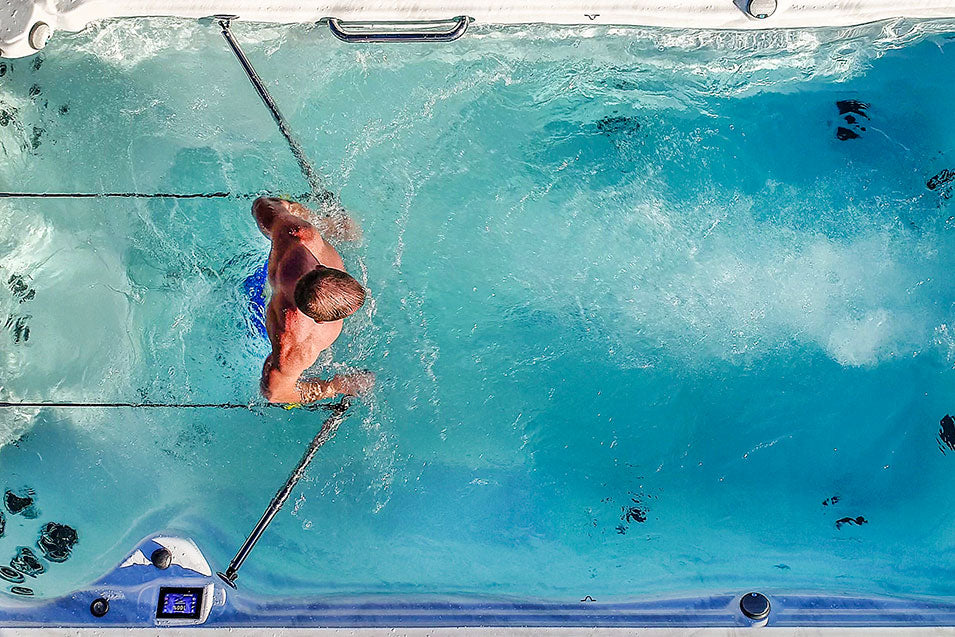 Obenansicht eines Swim Spas mit einem Mann, der Wassergymnastik macht.