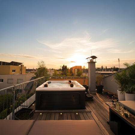 Whirlpool auf einer Dachterrasse bei Sonnenuntergang, mit urbanem Ausblick und gemütlicher Sitzlandschaft.